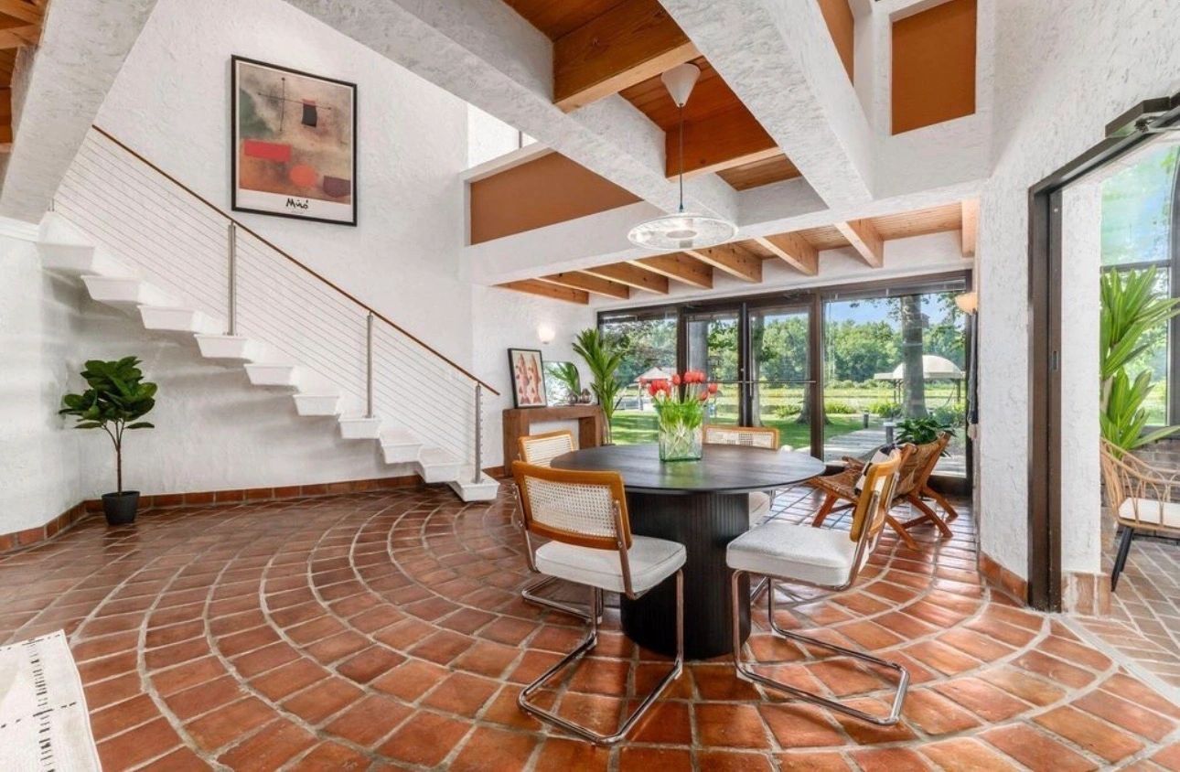 Dining table and cane chairs beneath wood beams, with terracotta floors and garden-facing windows in Buckeye Lake