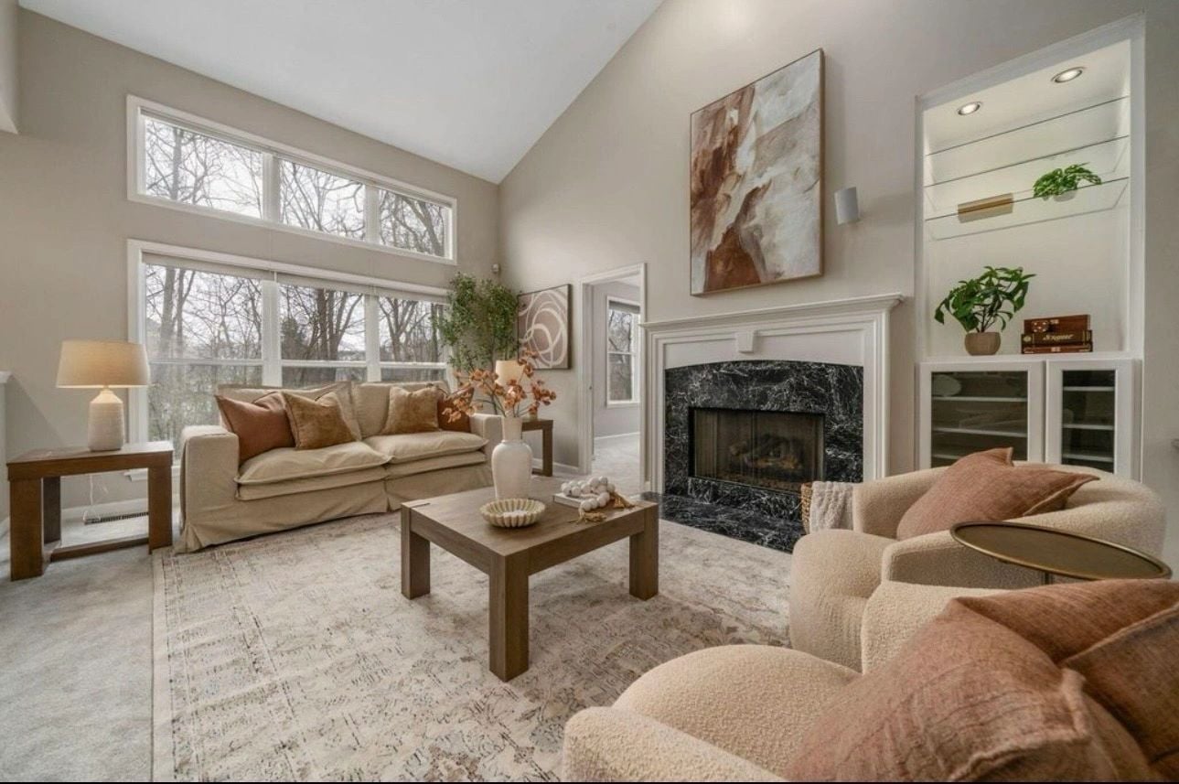 Cream sofa and armchairs around a black marble fireplace beneath vaulted ceilings in Powell